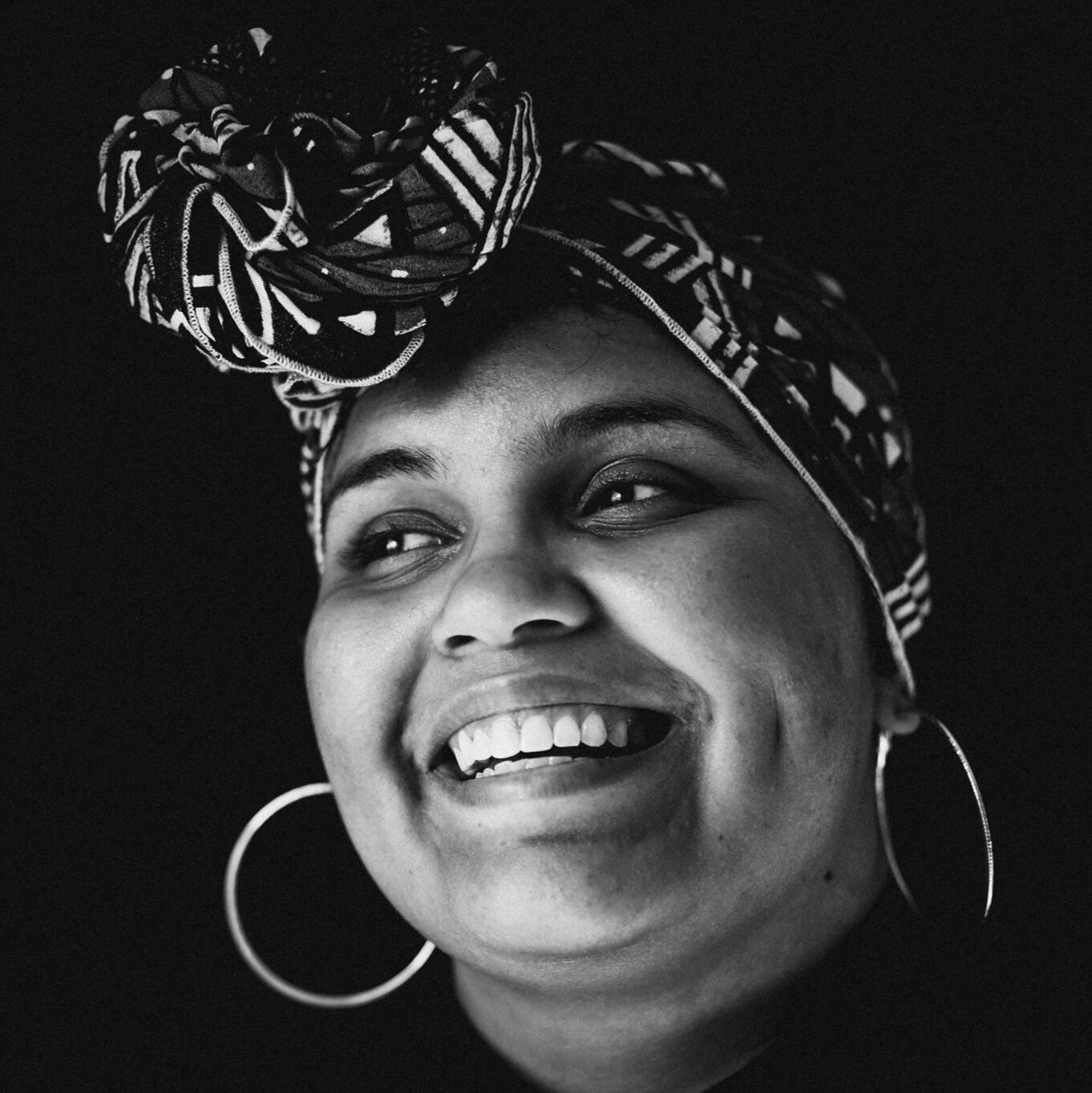 A black and white headshot of Bunny Morgan-Brown wearing a geometric headwrap, taken by photographer Jacquelyn Tierney.