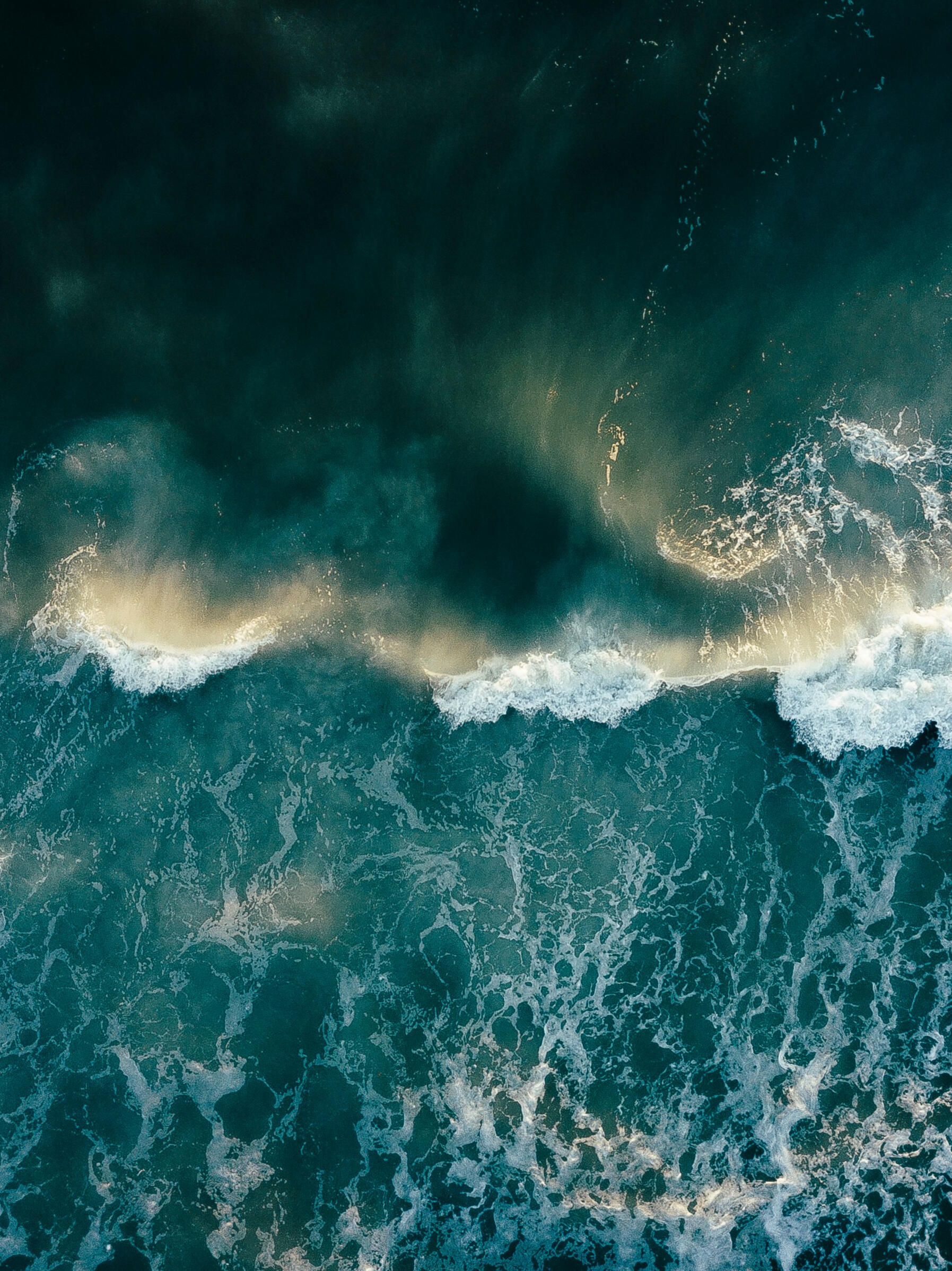 An image of a dark green and teal ocean at sunrise
